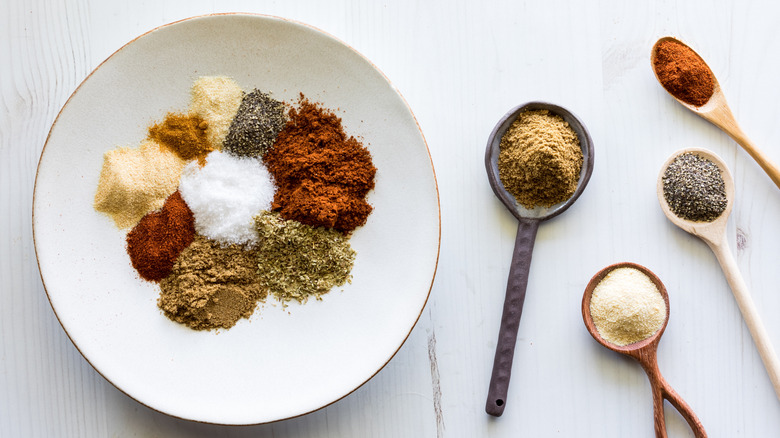 taco seasoning mix in a plate with several spoons filled with spices on the side