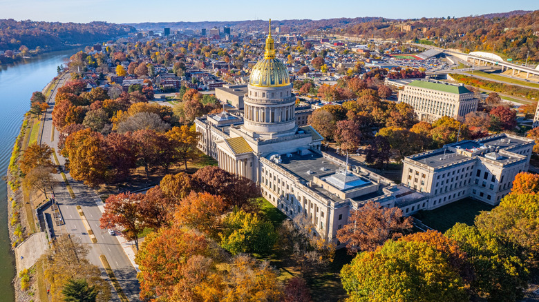 An aerial photo of the West Virginia Capitol building along a river in fall