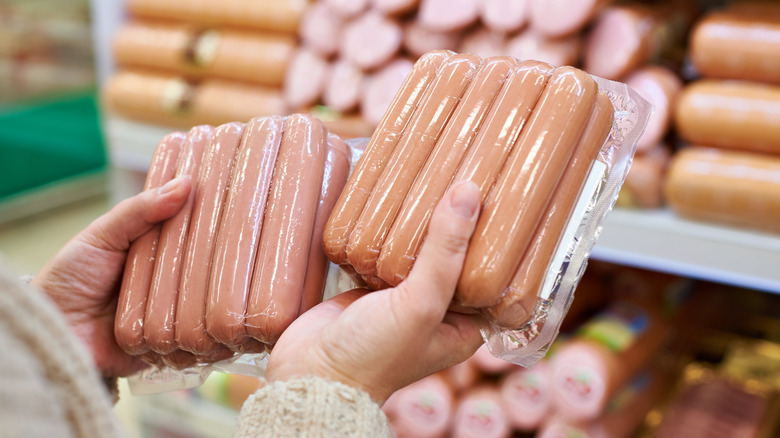hands holding packages of hot dogs
