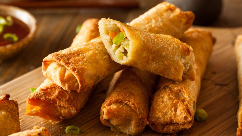 Close-up of a stack of egg rolls on a wooden board