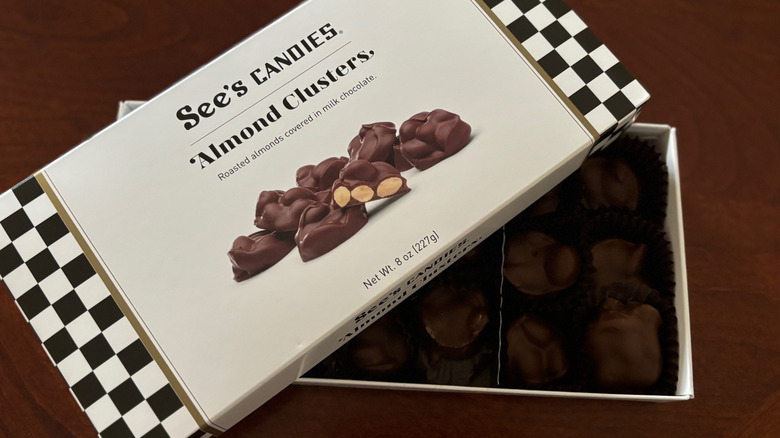 an open box of See's Candies almond clusters on a wooden table