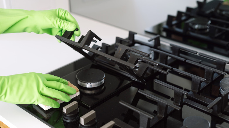 Gloved hands clearning gas stove