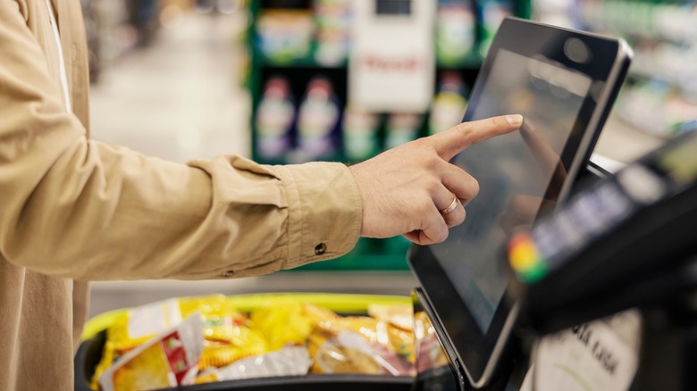 Close-up of a person's arm using self-checkout at a grocery store 