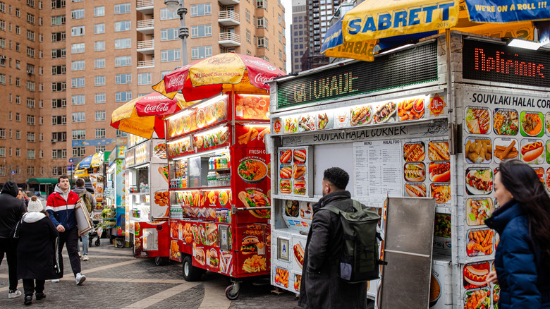 people gathering outside of New York street cart for food