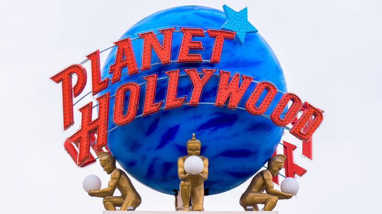Planet Hollywood sign with red lettering against a blue planet shape.