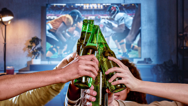 Hands holding beer in front of TV