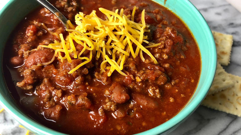 Bowl of chili topped with cheese with a spoon