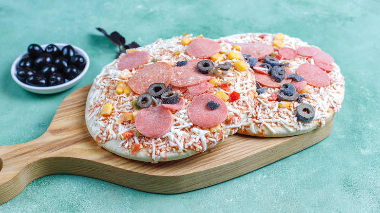 frozen pizzas on cutting board