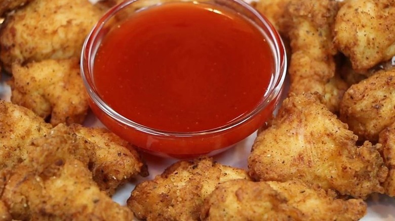close up of a small bowl of Polynesian sauce next to grilled chicken