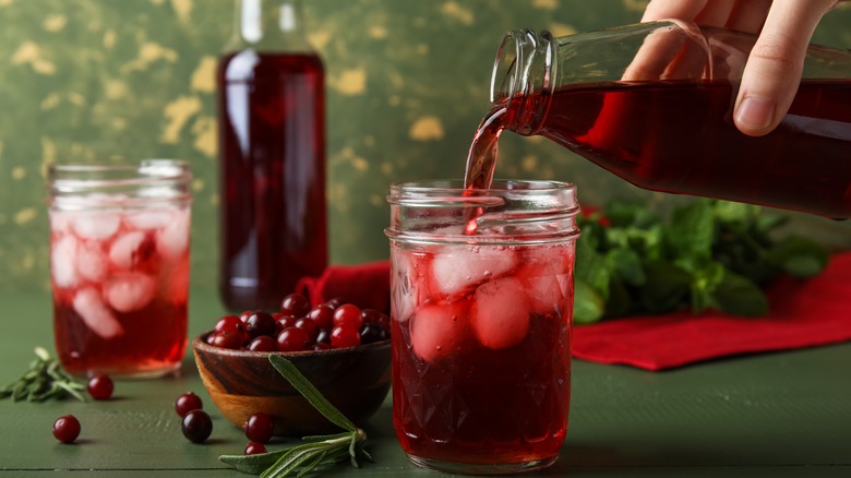 person pouring cranberry juice in glass