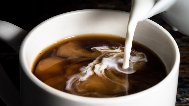 Pouring creamer in coffee