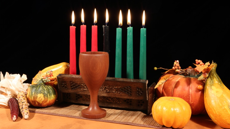 Kwanzaa candles and symbolic unity cup and corn with a black backdrop