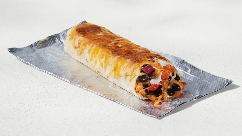 A Taco Bell Black Bean Grilled Cheese Burrito resting on a piece of foil against a neutral background