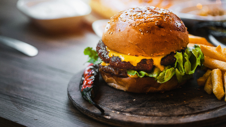 A cheeseburger on a plate beside fries and a roasted red pepper