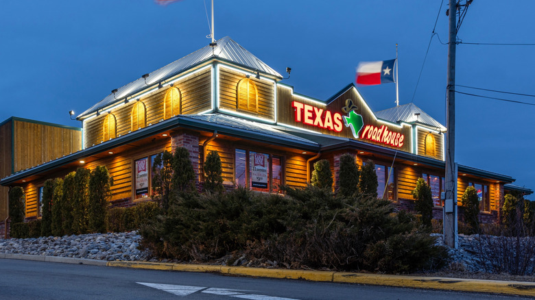 Lit up exterior of Texas Roadhouse with American and Texan flags
