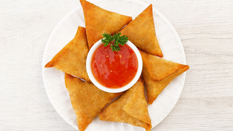 Plate of samosas with red sauce 