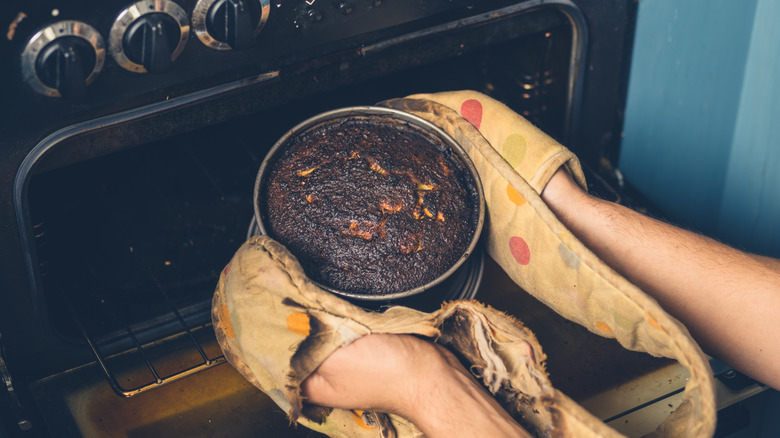 Person pulling burned cake from oven