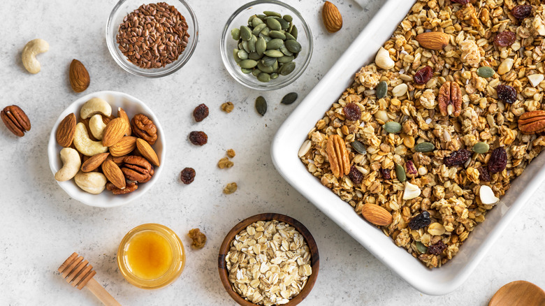 Casserole dish of granola and bowls of nuts and seeds