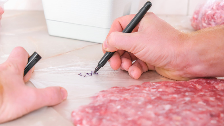 Person with marker writing on freezer bag with ground beef
