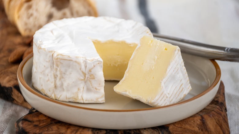 Plate of soft French Camembert cheese with bread in the background