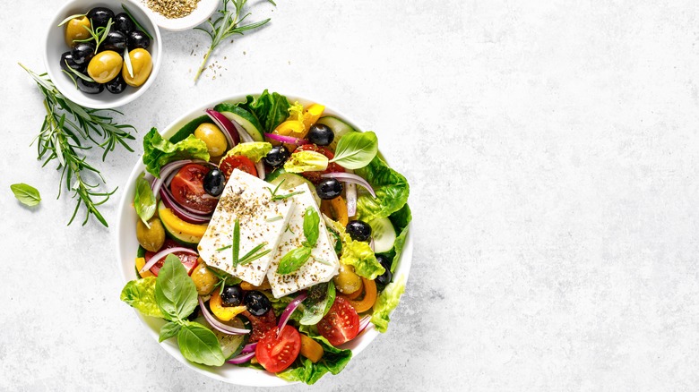 Bowl of salad with two blocks of feta cheese in the center