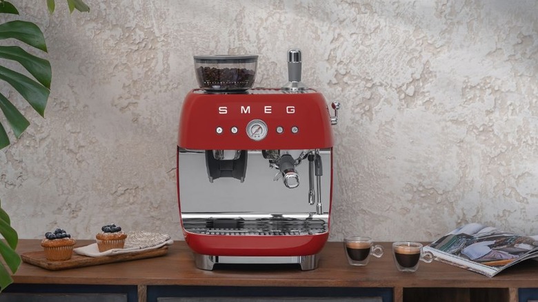 A SMEG Semi-Automatic Espresso Machine on a counter next to a plate of muffins and two espressos