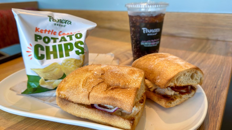 Panera sandwich, chips and drink on a plate.