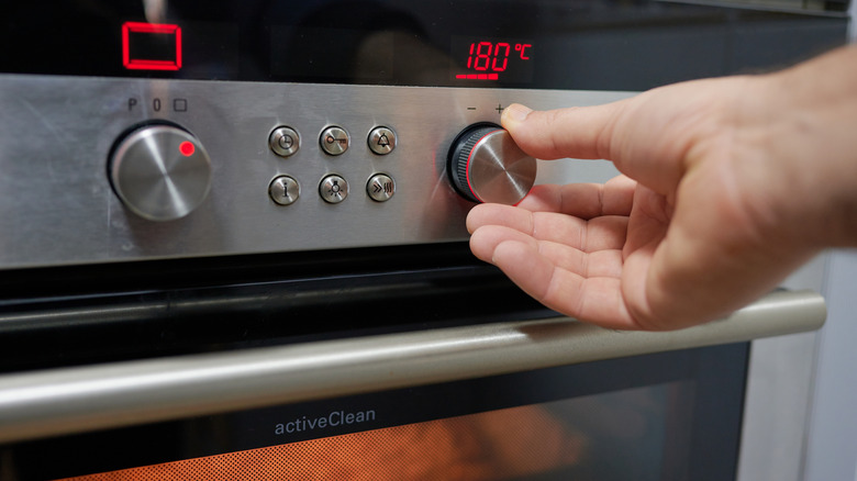 hand turning oven dial to 180 degrees Celsius