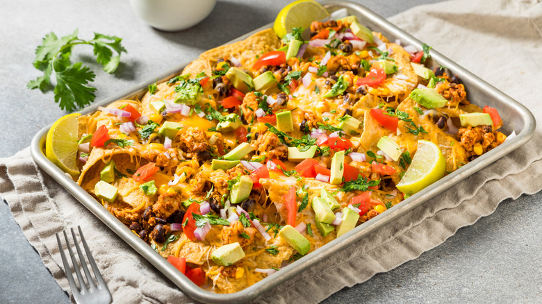 Tray of baked nachos with lemon wedges