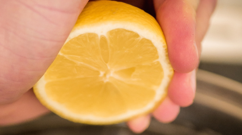hand squeezing half a lemon
