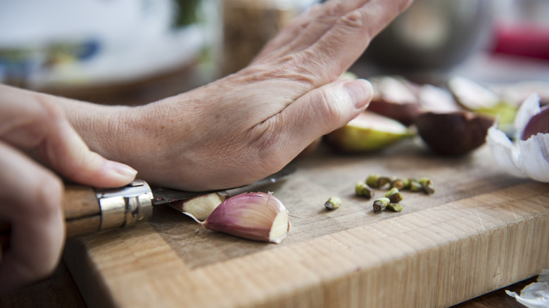woman smashing cloves of garlic with a knife