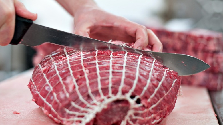 Person cutting raw beef 