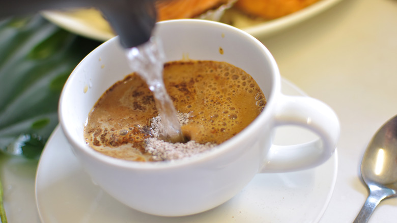 hot water poured into cup of instant coffee