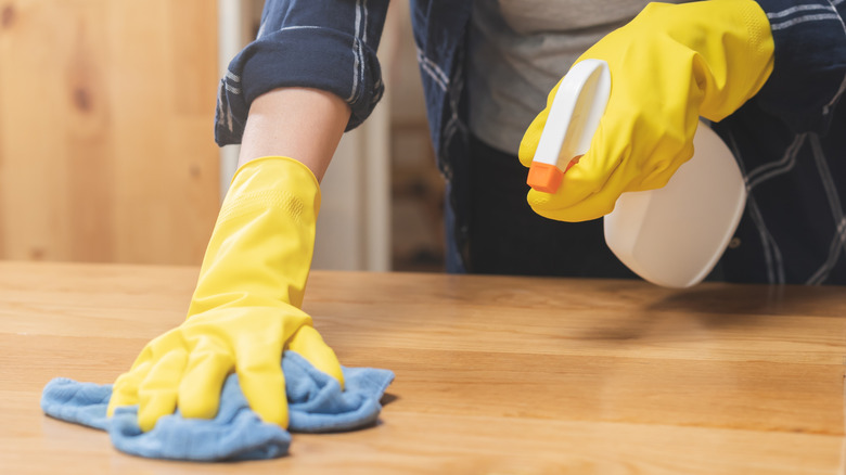 Woman spraying and cleaning wooden countertops