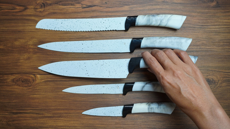 hand reaching for cooking knife on wooden counter