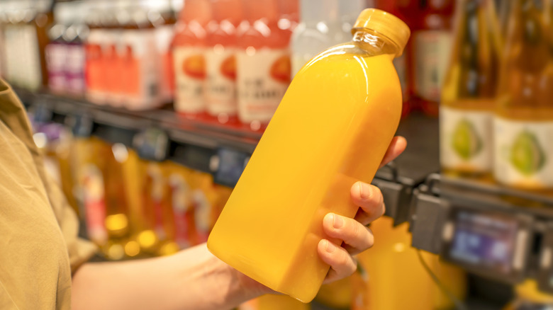 person holding orange juice in grocery store