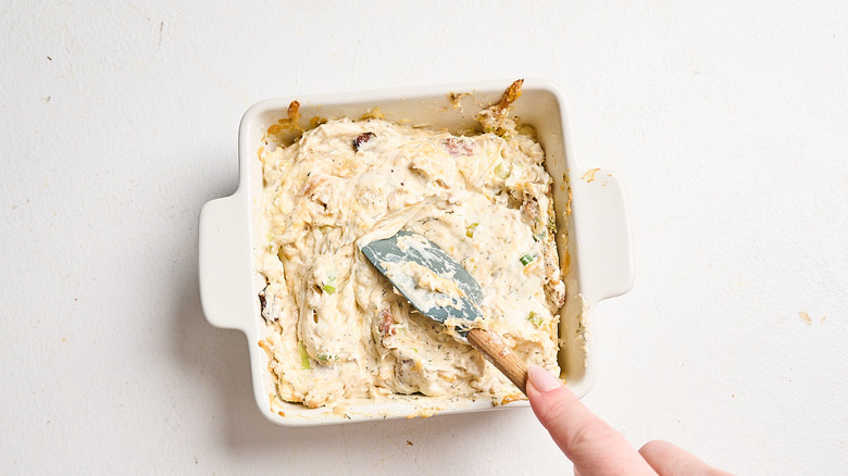 stirring chicken bacon ranch dip in casserole dish