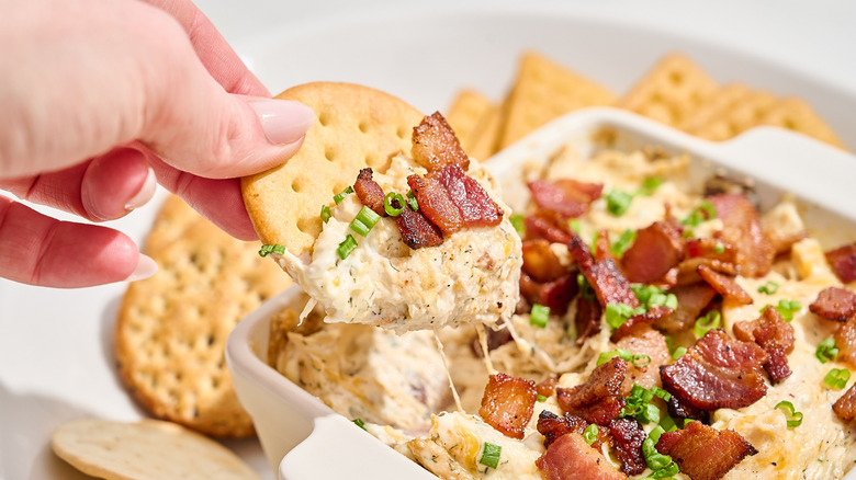 Scooping chicken bacon ranch dip with a cracker