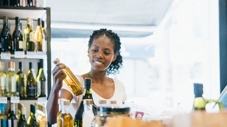 Woman looking at olive oil bottle in store