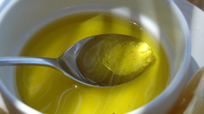 Olive oil pooling in small bowl and spoon