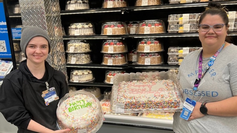 Sam's Club employees holding cakes in front of the cake case at Sam's Club