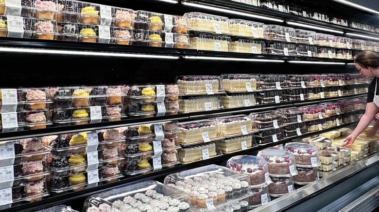 Sam's Club cupcake and cake refrigerator case with employee adding a cake