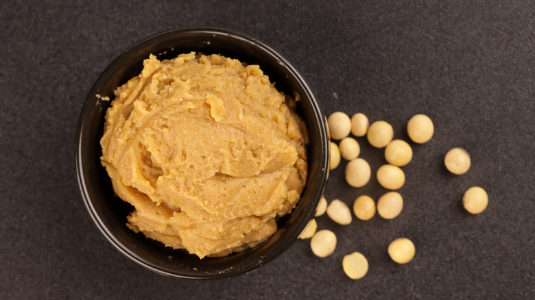 Dish of miso paste beside soybeans