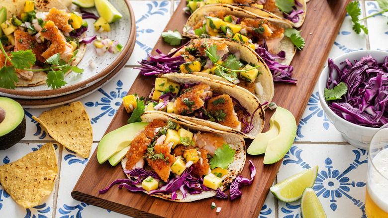 A brightly colored array of tacos with purple cabbage and avocado