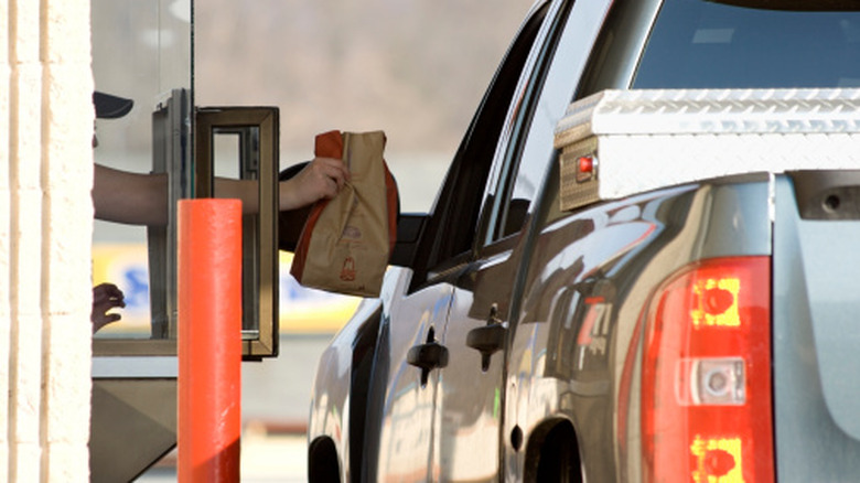 Person hanging a bag to a customer in a truck at the Arby's drive-thru