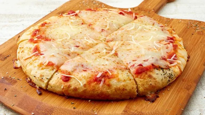 A Double Cheese pizza pie from Schlotzsky's sitting on a wooden cutting board