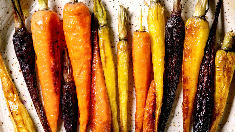 a plate of grilled orange, yellow, and purple carrots