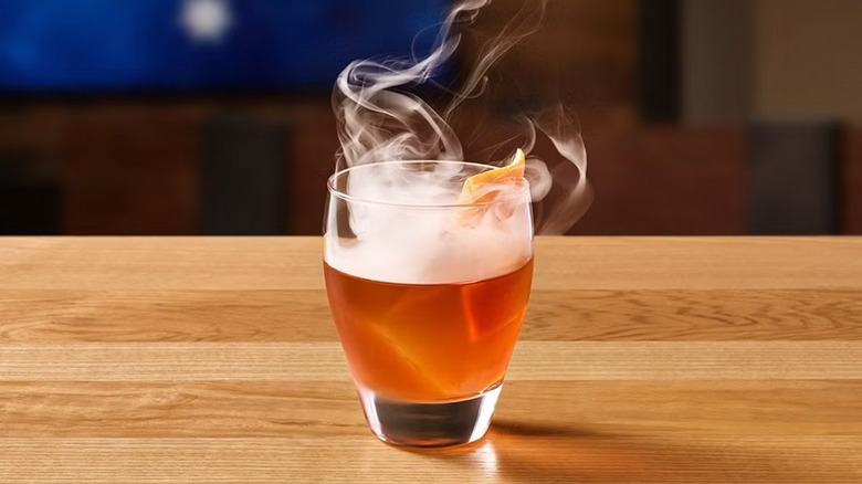 A smoked old fashioned sit on a wooden table at Outback Steakhouse