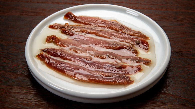 A small dish of anchovies sitting in oil