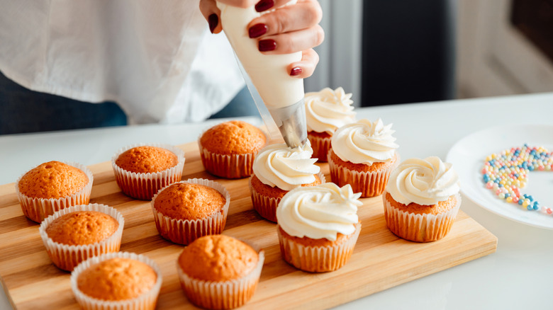 baker putting icing on cupcakes